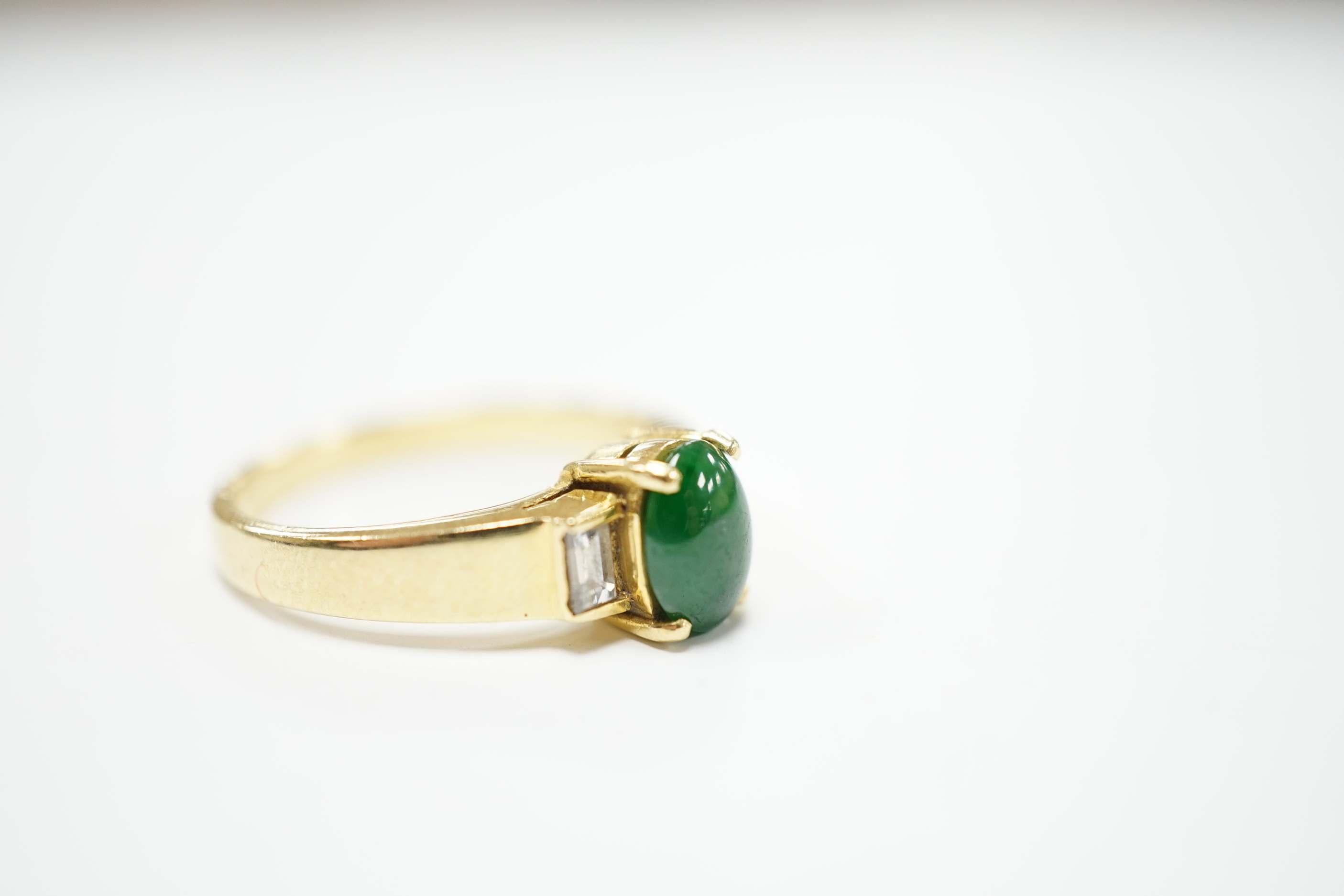 A 750 yellow metal, single stone cabochon jade and two stone baguette cut diamond set ring, size M, gross weight 4.8 grams.